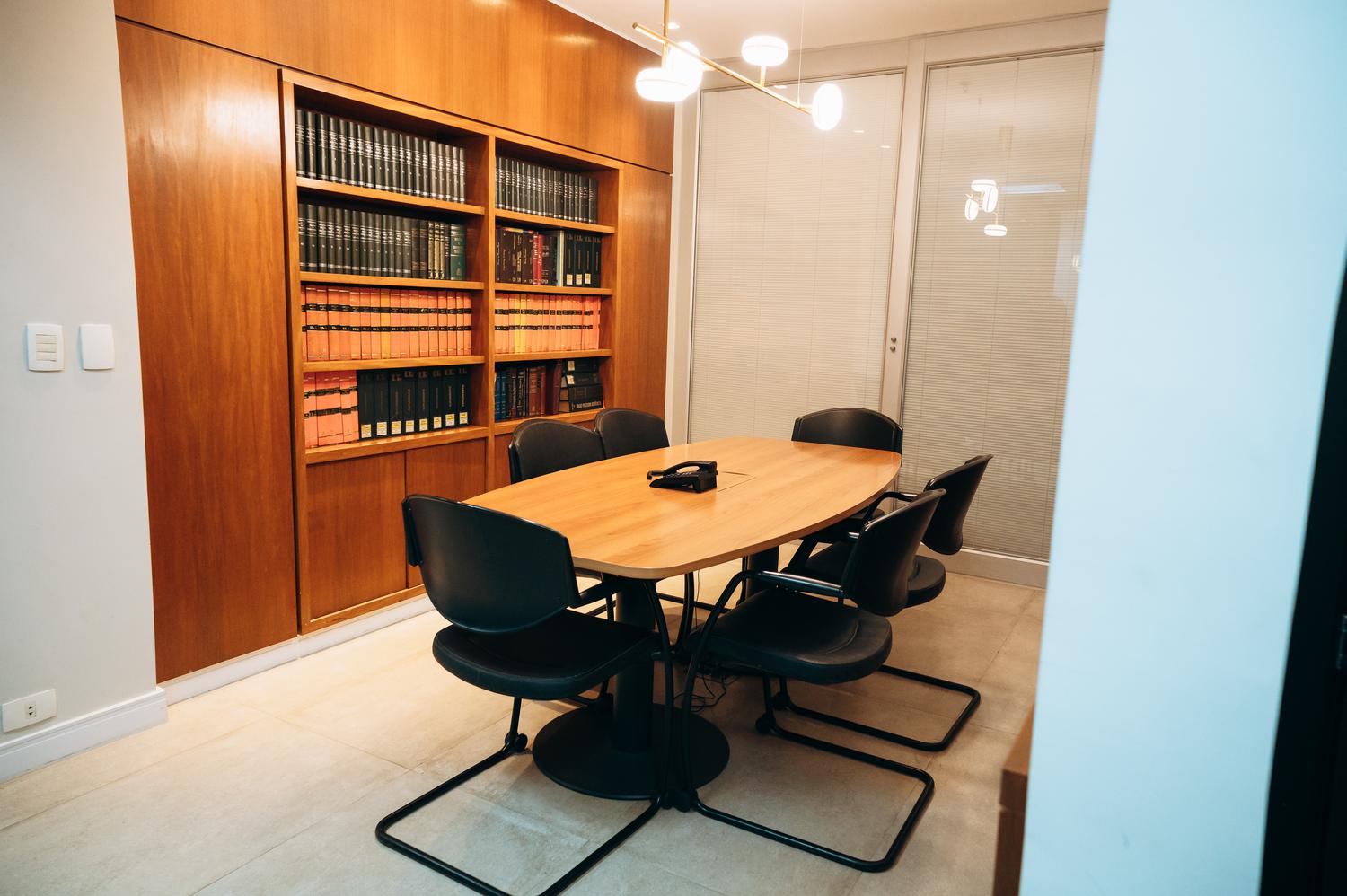Sala de reunião do escritório, com a biblioteca jurídica